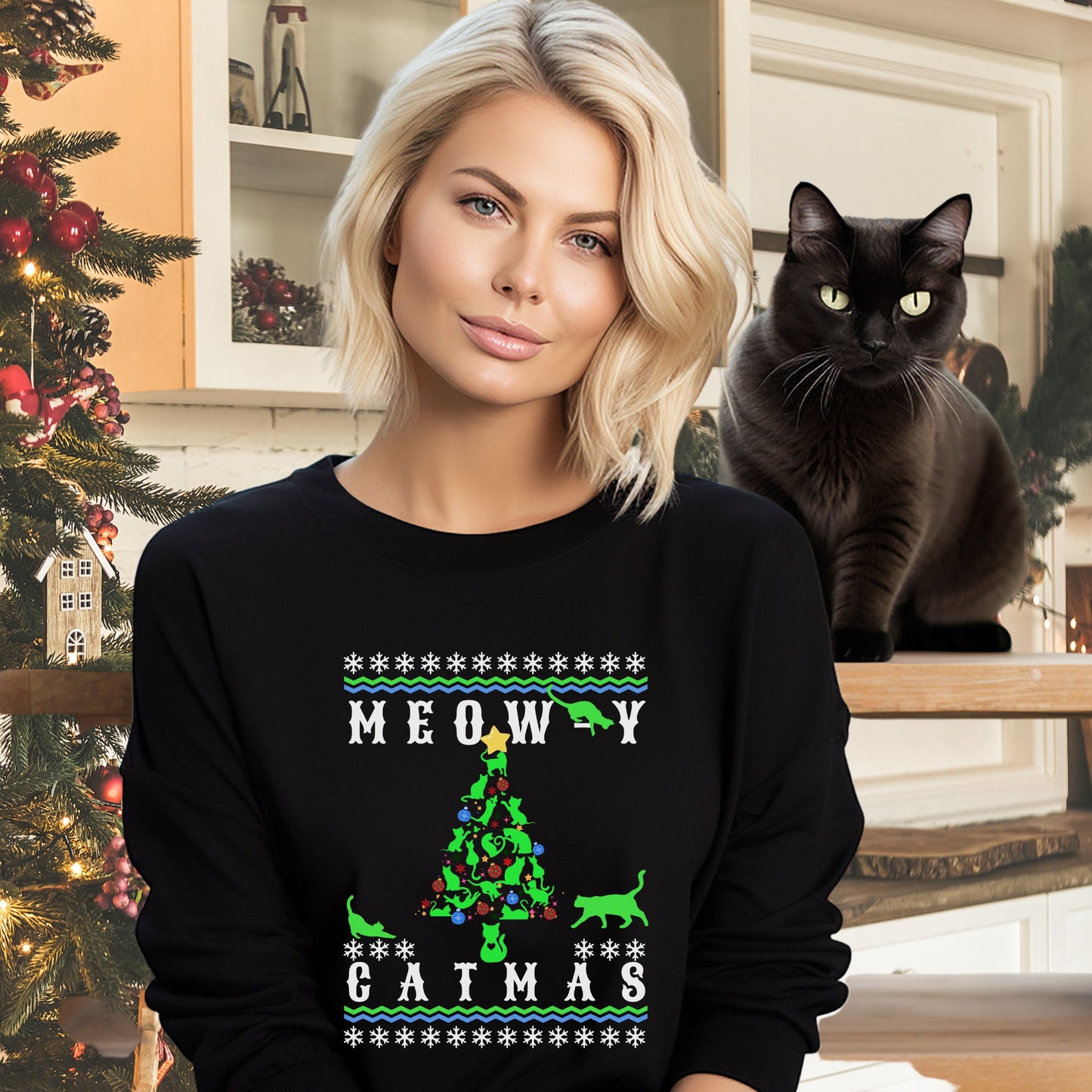 "Model wearing a black 'Meowy Catmas' holiday sweatshirt with a whimsical cat-themed Christmas tree design, paired with a beige knitted beanie, posing next to a decorated pine tree."