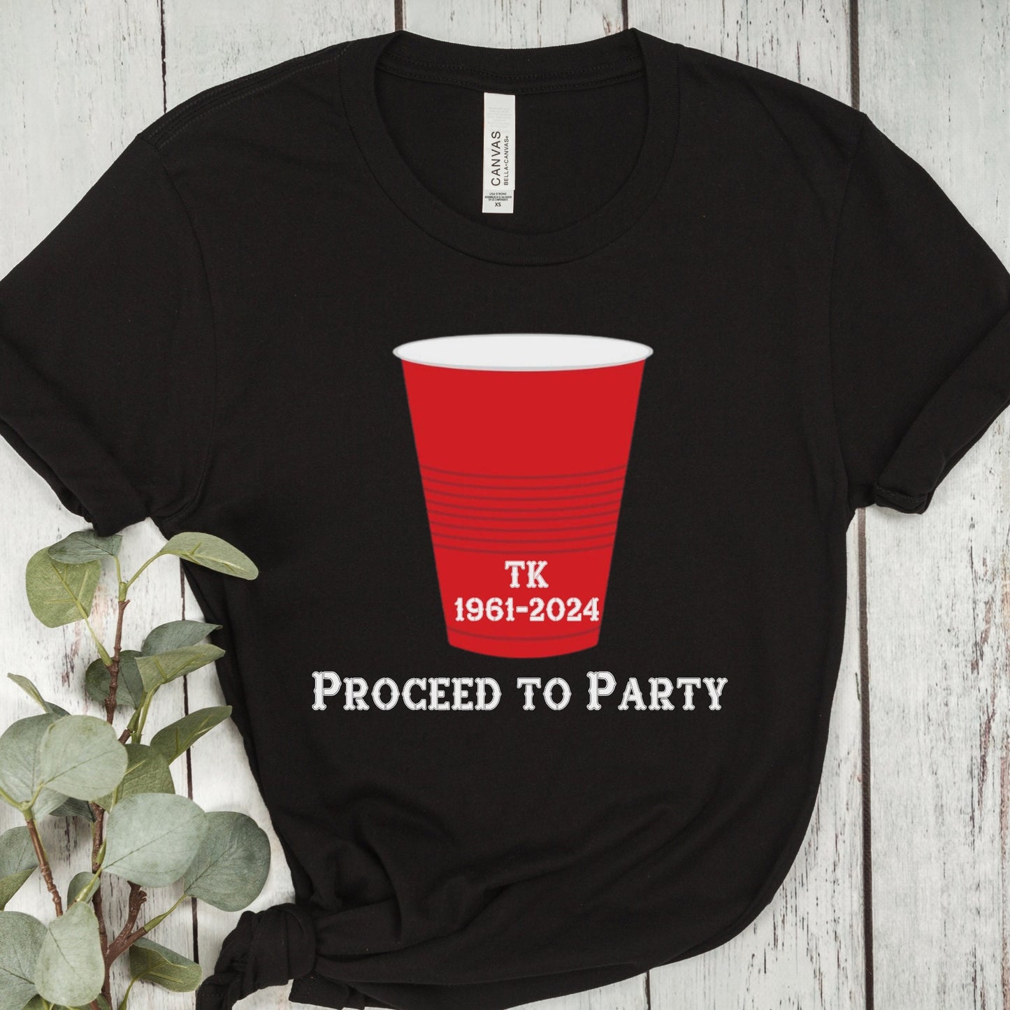 Black T-shirt with a red party cup graphic and text. The cup has the initials TK and the years 1961-2024 printed on it